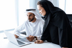 Middle Eastern business colleagues in traditional attire collaborating on a laptop in a bright professional setting